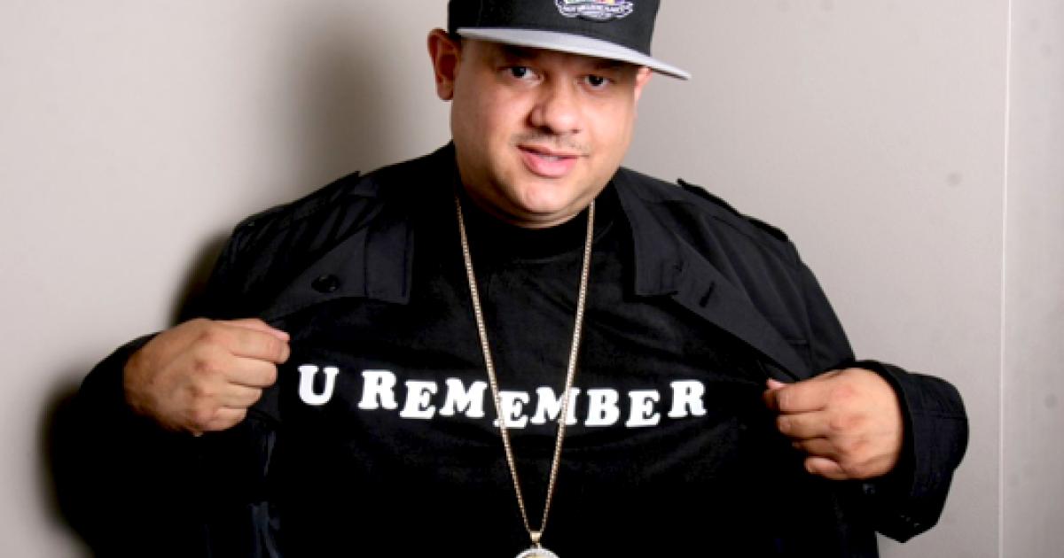 Dj ted smooth smiles at the camera wearing a shirt that says "U REMEMBER."